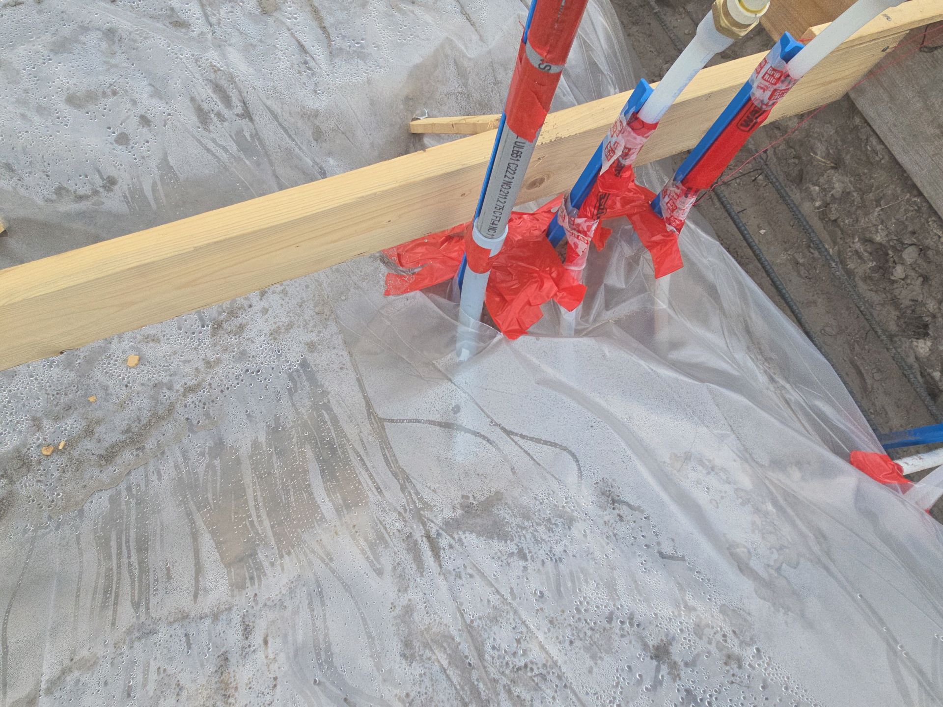 Plumbing stub-ups through a taped vapor barrier with standing water before the pour