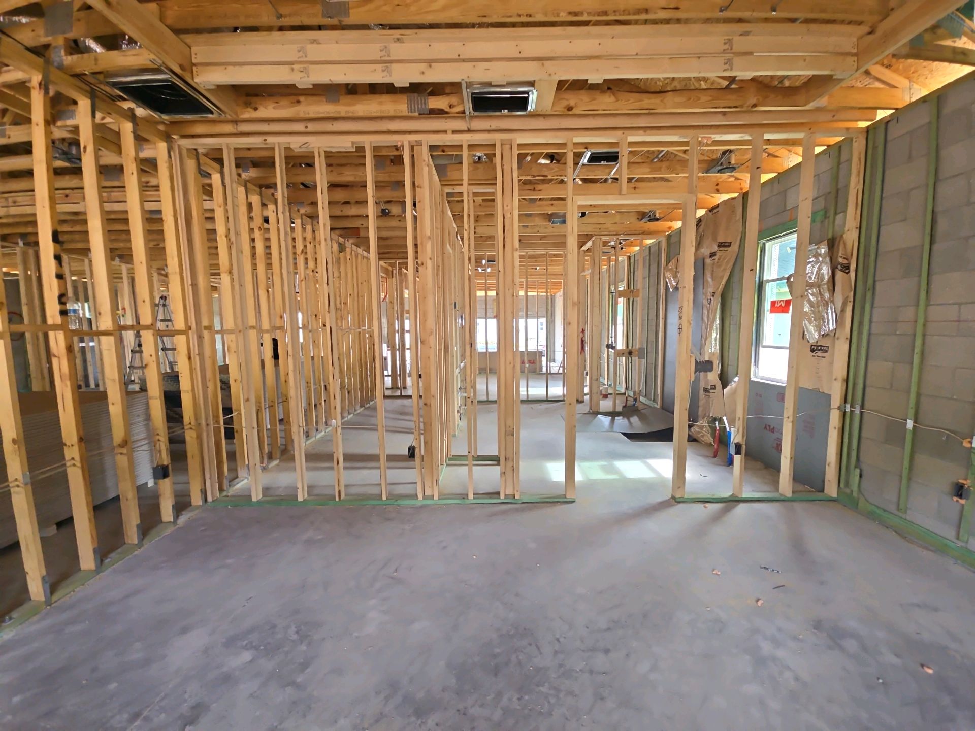 Interior wall framing at pre-drywall, with stud walls, ceiling framing and furred block walls all open