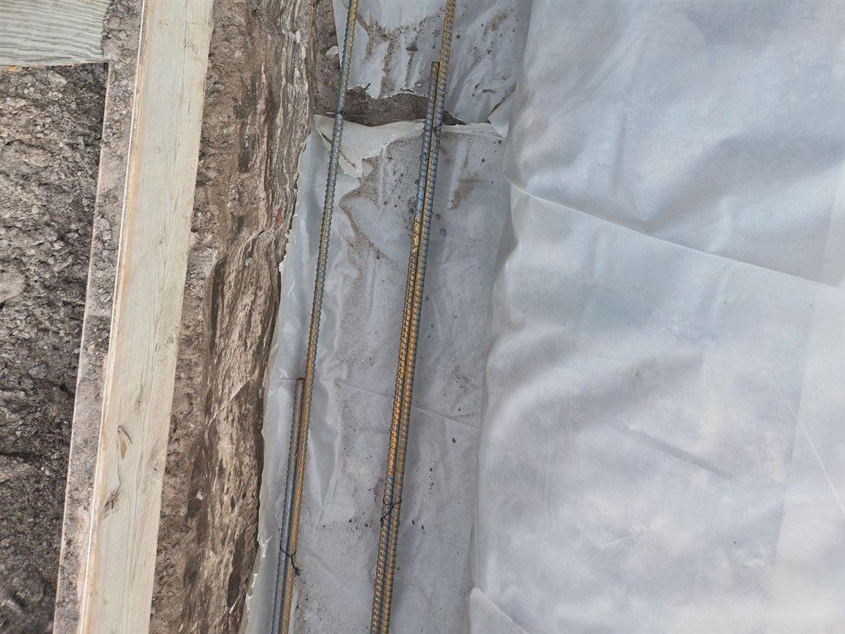 Footing reinforcement lying on the soil in the trench, with nothing holding it at depth