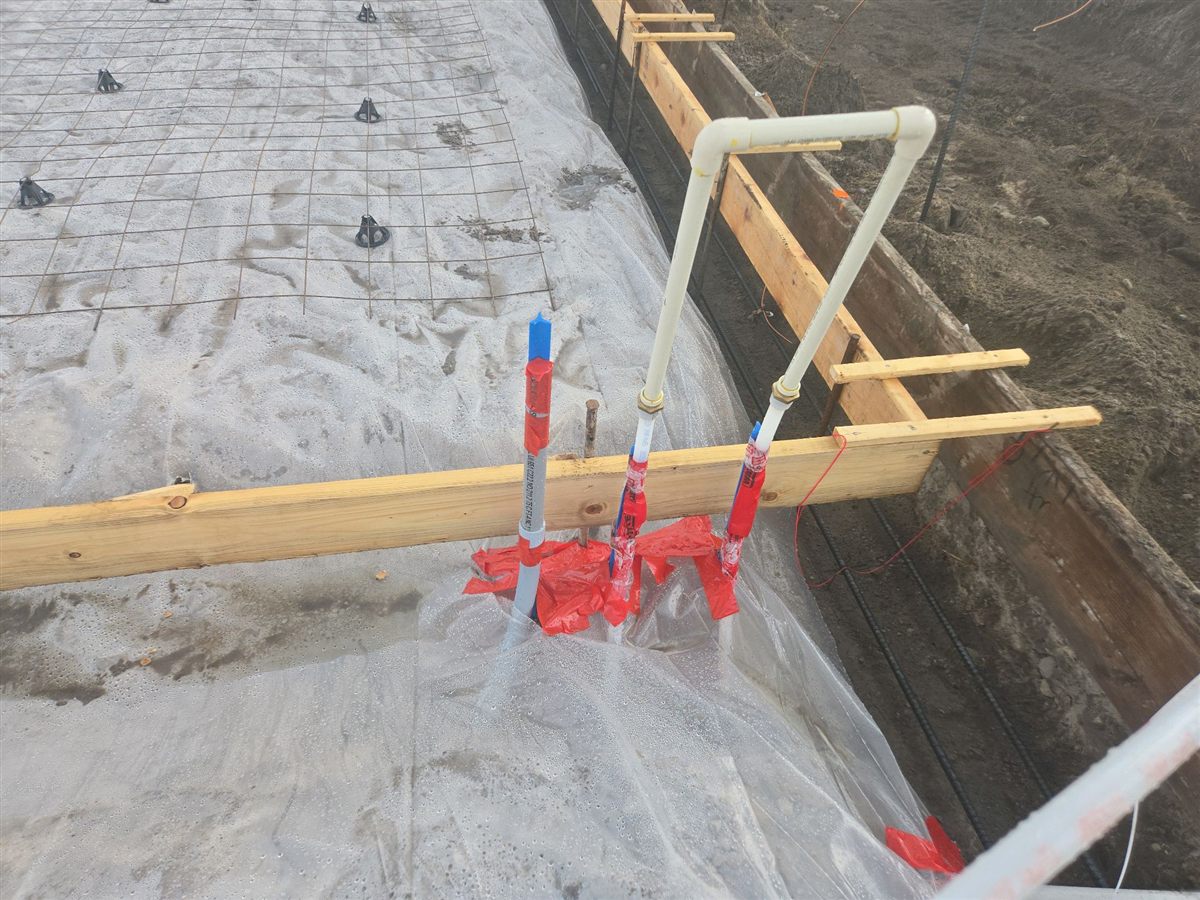 Under-slab stub-ups at the form edge, marked and checked against the plan before the pour