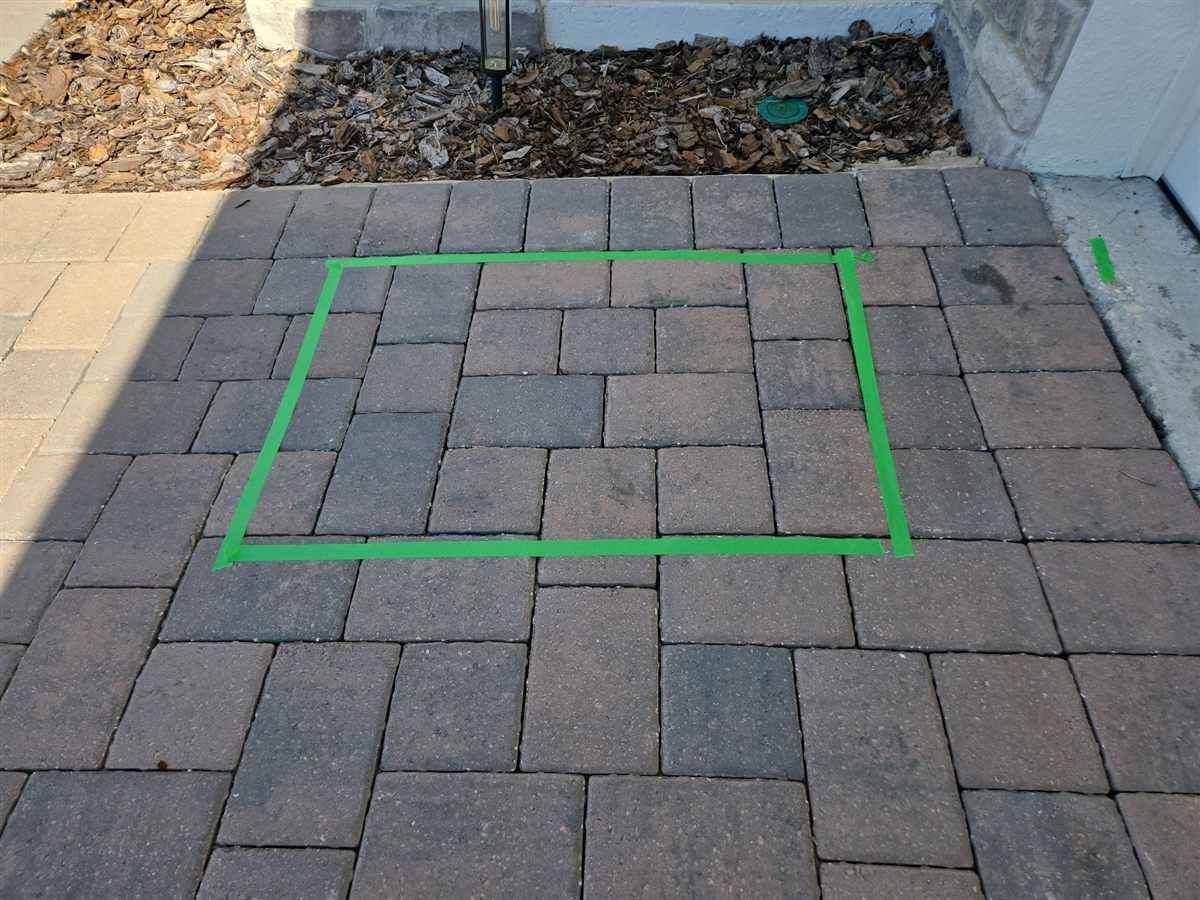 A settled area in a paver walkway, outlined with tape
