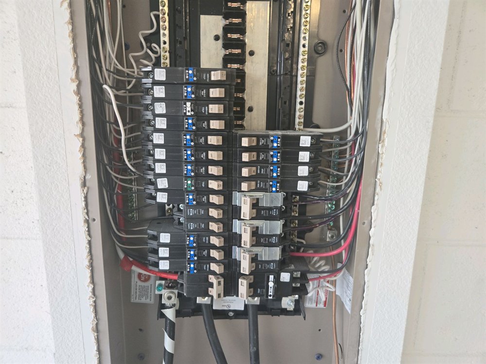 Electrical panel with the cover removed, showing breakers, neutral and ground bars, and the service conductors entering at the bottom