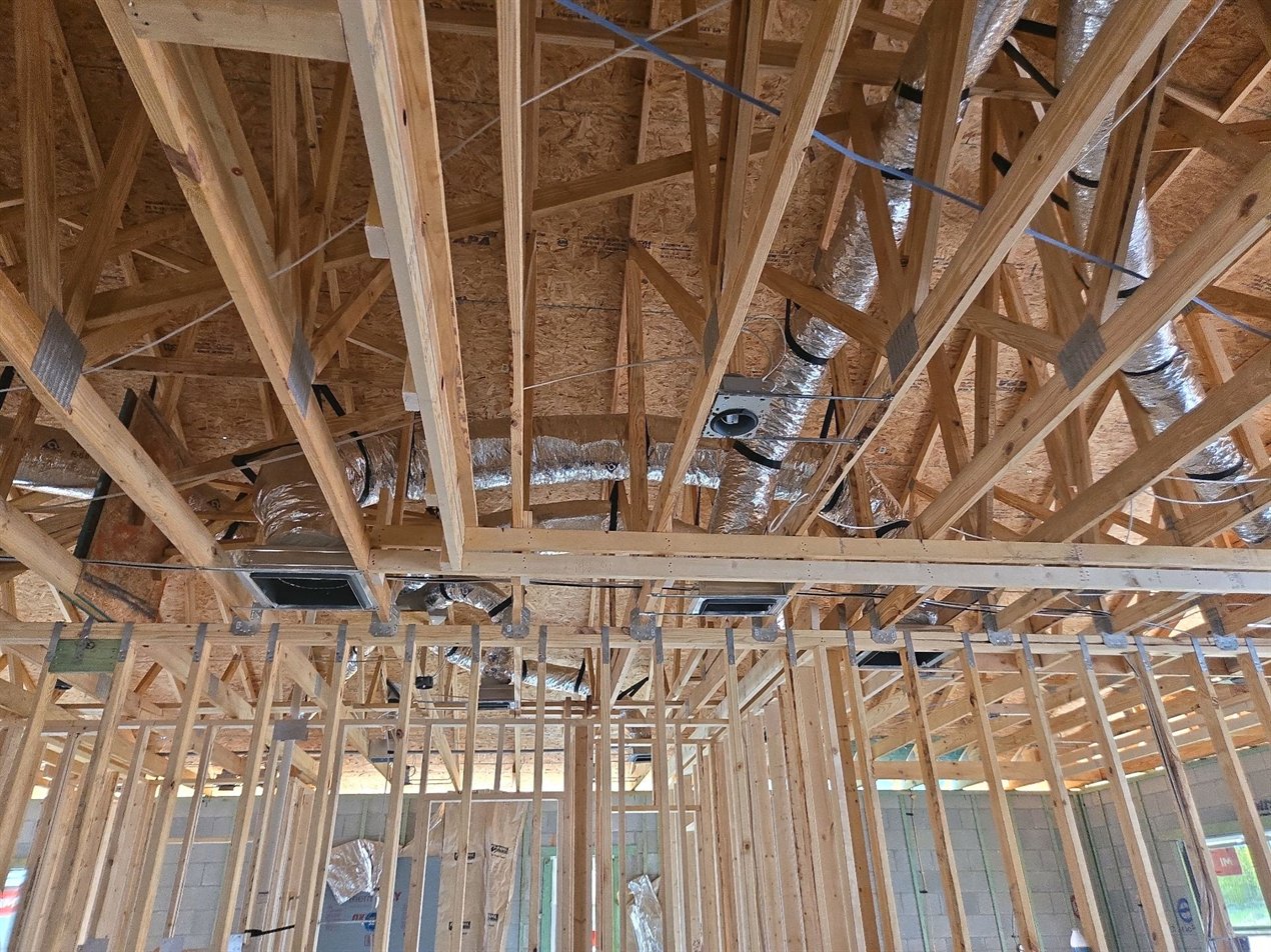 Roof trusses, connector plates and flexible ducts seen from below before drywall